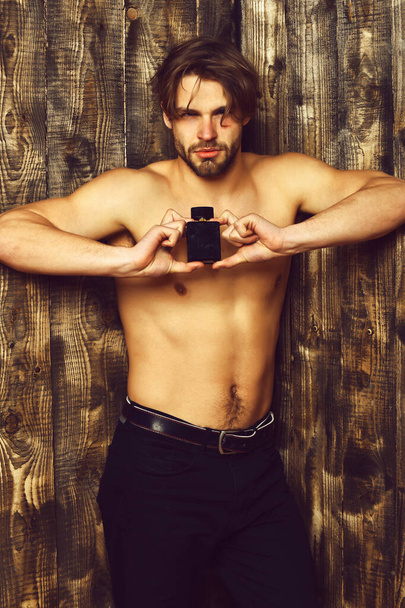 Caucasian bearded sexy macho man holding perfume - Fotografie, Obrázek