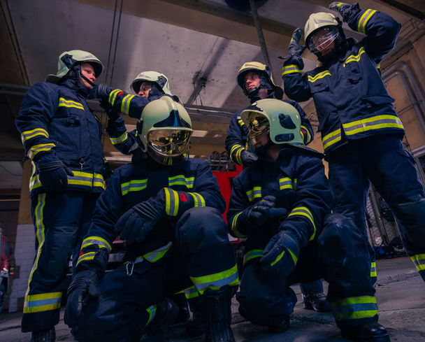 Retrato de bomberos de grupo frente al camión de bomberos dentro del interior del interior.  - Foto, imagen