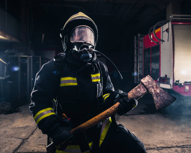 Ritratto di un pompiere donna mentre tiene in mano un'ascia e indossa
 - Foto, immagini