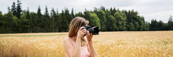 Νεαρή γυναίκα με επαγγελματική κάμερα dslr που τραβάει φωτογραφίες έξω  - Φωτογραφία, εικόνα