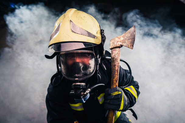 Πορτραίτο γυναίκας πυροσβέστη ενώ κρατά τσεκούρι και φοράει - Φωτογραφία, εικόνα