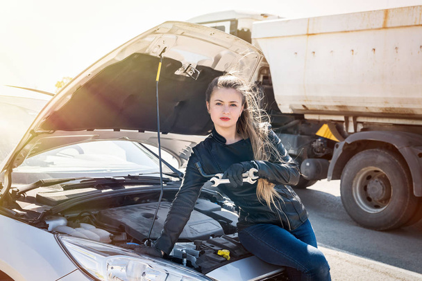 Beautiful woman driver with wrenches sitting on broken car - Photo, Image