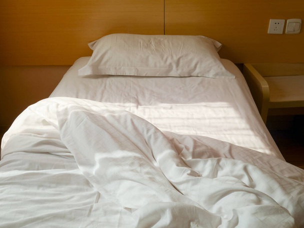 Cama sin hacer con edredón arrugado, sábana y almohada
 - Foto, imagen