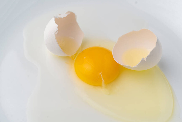 разбитое белое яйцо в тарелке, чтобы приготовить некоторые блюда
 - Фото, изображение