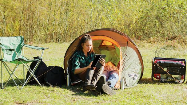 Piękna młoda dziewczyna używa tabletu przed namiotem kempingowym - Zdjęcie, obraz