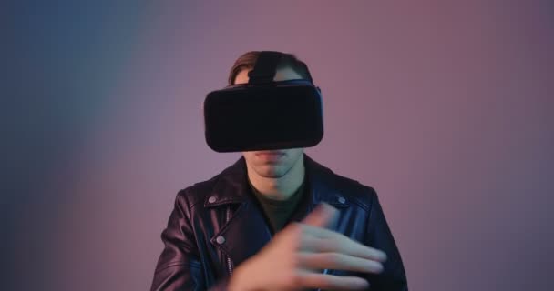 Primo piano del maschio con VR Glassess nella luce al neon multicolore. Ritratto di un giovane uomo in casco realtà virtuale in luci al neon futuristiche
. - Filmati, video
