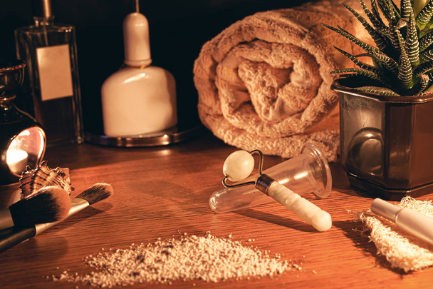 Luxurious jade massager and facial massage jar. Composition of massager and massage jar from aging on the women's table. The concept of natural skin care. Stock photo. - 写真・画像