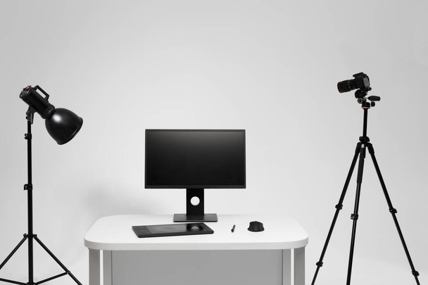 Photographer working place in photo studio with lighting equipment. Camera on the tripod. PC computer on desk. Designer working place. - Photo, Image