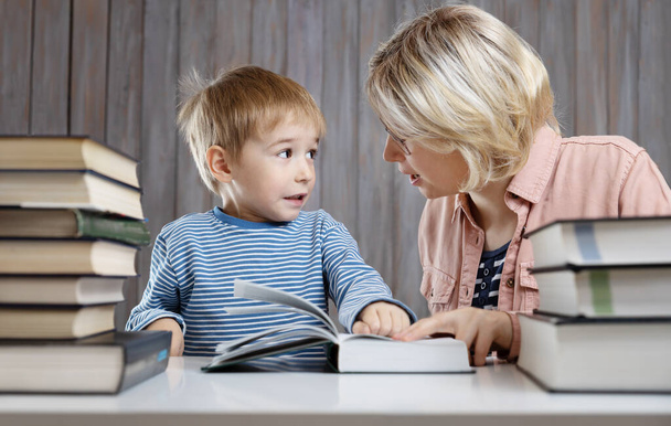 five years old child reading a book at home with mother - Foto, immagini