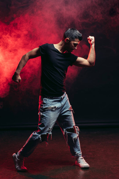 handsome young male dancing isolated in red smoky space - Foto, imagen