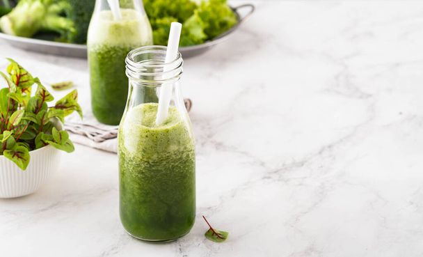 Blended green smoothie with ingredients on the white table. - Photo, Image