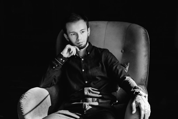 barbudo chico en traje de negocios se sienta en sillón en negro y whi
 - Foto, imagen