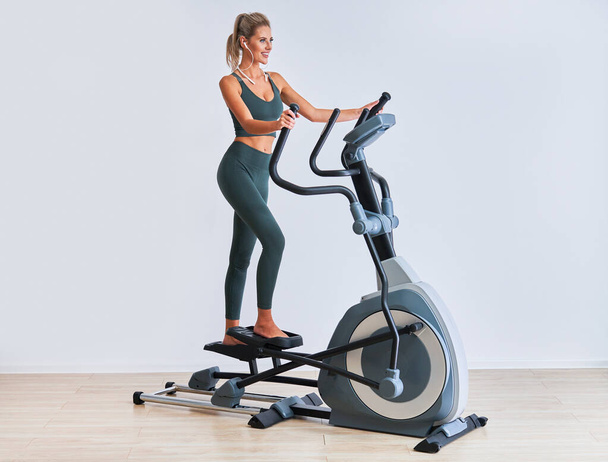 Woman exercising at the gym on crosstrainer - Photo, image