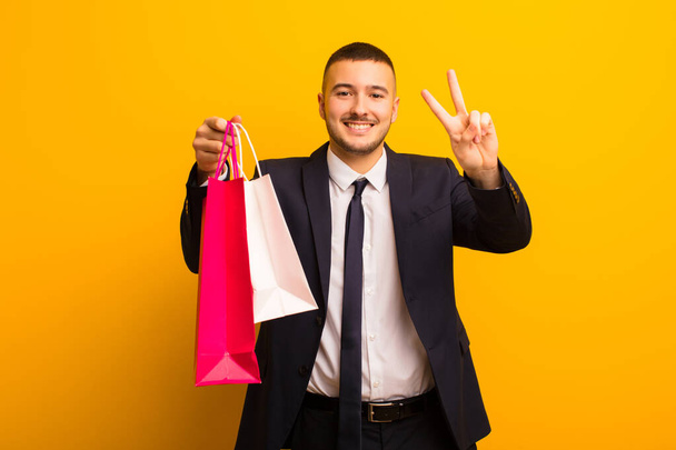 young handsome businessman  against flat background with shopping bags - Foto, afbeelding