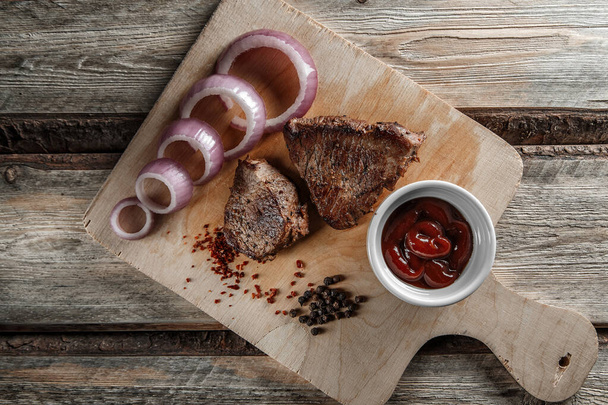 carne alla griglia con spezie e salsa di pomodoro su uno schienale di legno usurato
 - Foto, immagini