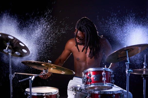 Drummer black male musician hitting on wet drum cymbal and water splashing in slow motion - Photo, Image