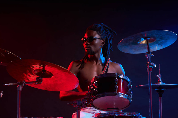 expressive artictic black man playing drums isolated over neon background - Foto, immagini