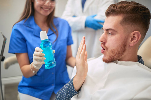 Улыбающийся доктор дантист показывает полоскание рта пациенту
 - Фото, изображение