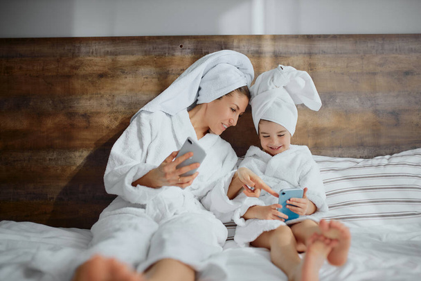 female in bathrobe spend time with daughter after shower - Foto, Bild