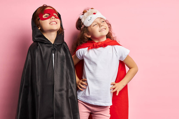 Two little superheroes looking up isolated over pink background - Photo, Image