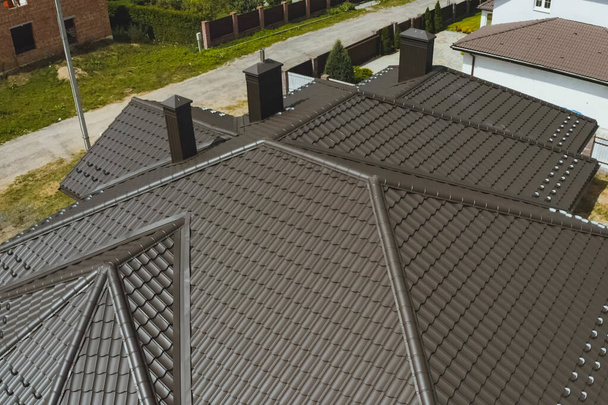 Casa con un tetto in metallo marrone. Tetto in metallo ondulato e metallo ro
 - Foto, immagini
