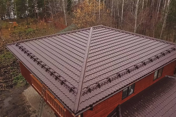 Casa con un tetto in metallo marrone. Tetto in metallo ondulato e metallo ro
 - Foto, immagini
