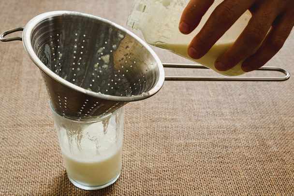 Мужская рука наливает молочный кефир в кувшин, чтобы приготовить здоровый бриа
 - Фото, изображение