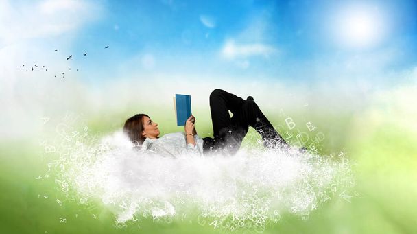 Μια επιχειρηματίας διαβάζει ένα βιβλίο πάνω από ένα σύννεφο φτιαγμένο από γράμματα. Έννοια της χαλάρωσης και της φαντασίας. - Φωτογραφία, εικόνα