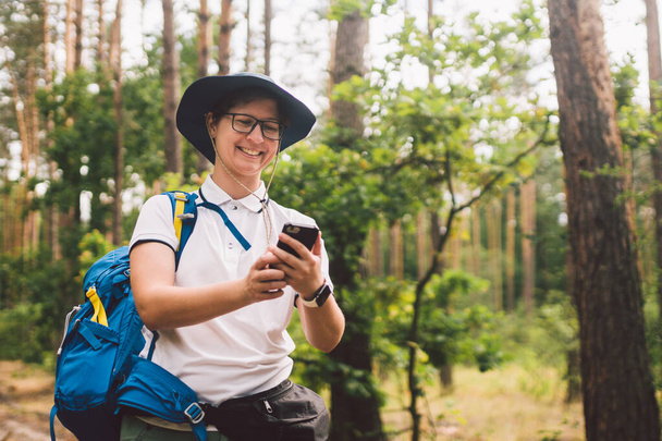 Girl tourist use smartphone on hike, looks maps and navigation. Woman with backpack using smart phone on beautiful nature.Travel concept. Outdoor travel. Travel and explore. Female Tourist Using gps - Photo, Image