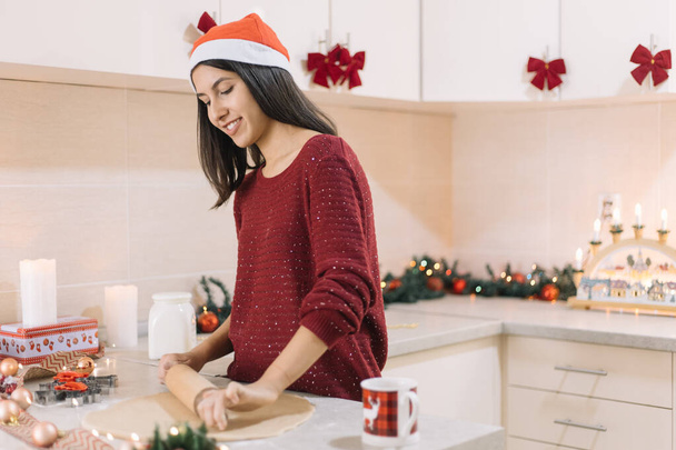 Girl making cookies in kitchen decorated for Christmas - Photo, Image