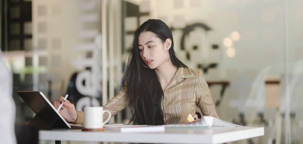 Portrét mladé krásné asijské designérky pracující na svém projektu při použití digitálního tabletu na moderním pracovišti - Fotografie, Obrázek