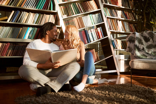 Άντρας και γυναίκα κοιτάζονται ενώ διαβάζουν. - Φωτογραφία, εικόνα