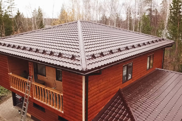 Σπίτι με καφέ μεταλλική στέγη.Κυματοειδής μεταλλική στέγη και μεταλλικό ro - Φωτογραφία, εικόνα
