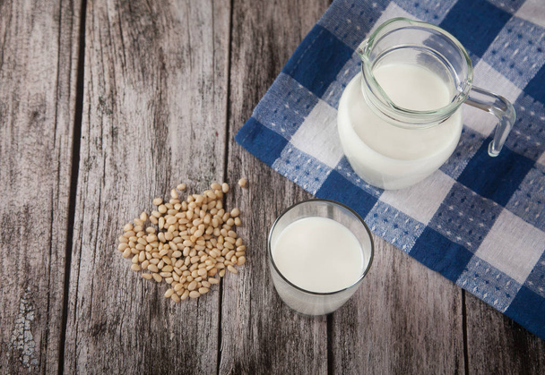 Vegetarian pine nut milk in a glass cup and jug on wooden background. Topview - Foto, afbeelding