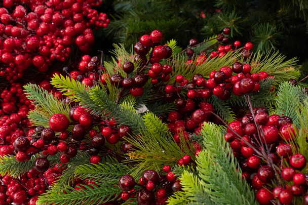 Stechpalme und Weihnachtsbaum. Neujahr Weihnachtsdekoration, Hintergrund. künstlicher Weihnachtsbaum und dekorative rote Beeren der Stechpalme - Foto, Bild