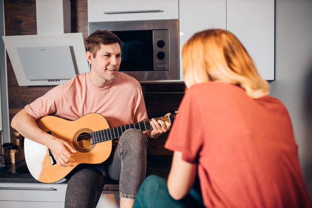 caucasian young woman and man sit together playing guitar - Foto, Imagem