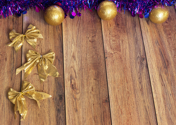 Τα δώρα είναι συσκευασμένα σε χαρτί Kraft και δεμένα με σατέν κορδέλα με χριστουγεννιάτικα παιχνίδια και μωβ tinsel σε ξύλινο φόντο. Διακόσμηση για το χριστουγεννιάτικο δέντρο. - Φωτογραφία, εικόνα