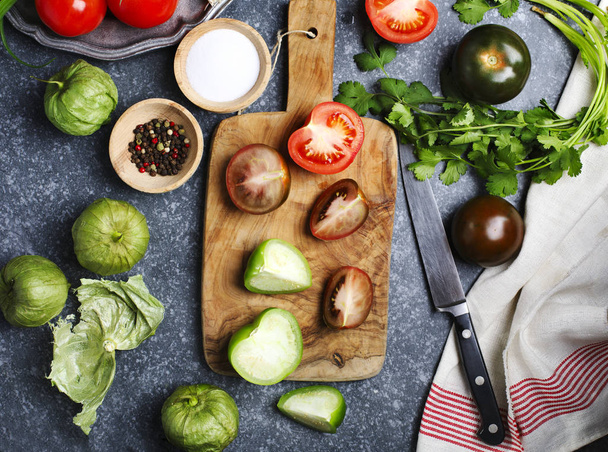 Chopped tomatoes and knife on cutting board, fresh vegetables on - Foto, afbeelding
