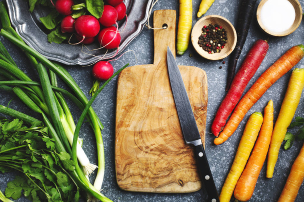 Légumes frais de printemps autour de la planche à découper en bois avec cuisine
 - Photo, image