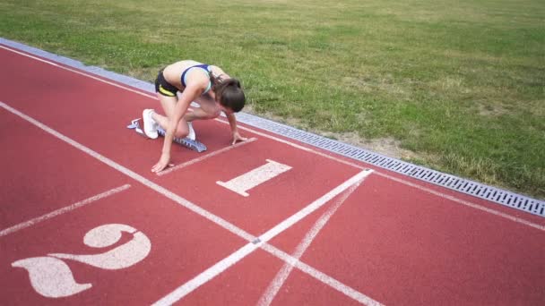 Uma jovem atleta começa a correr de quarteirão em estádio. Movimento lento, tiro firme
 - Filmagem, Vídeo