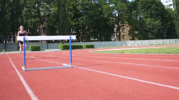 Zeitlupe .Athletin auf Kurs. Junge Läuferin trainiert mit Barrieren im Stadion.  - Filmmaterial, Video