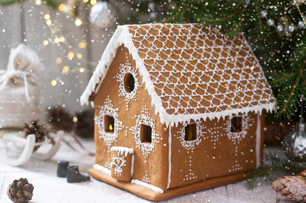 Gingerbread house and Christmas trees on a luminous background. Bokeh effect. - Фото, изображение