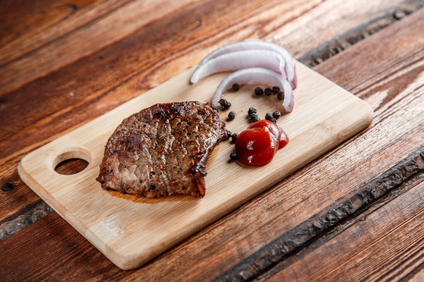 Мясо на гриле со специями и томатным соусом на изношенном деревянном бэкге
 - Фото, изображение