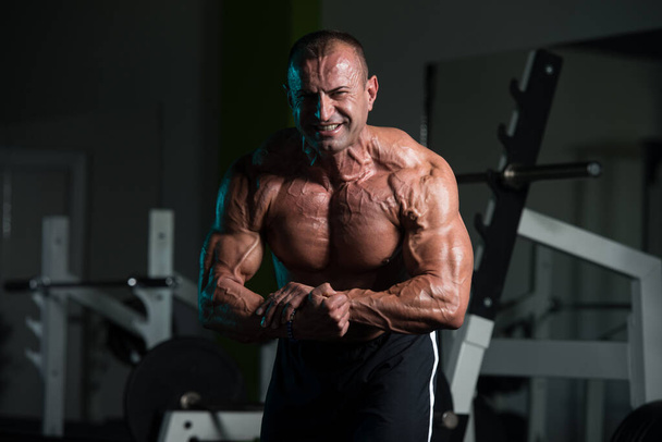 Ώριμος μυϊκός άνθρωπος κάμψη των μυών στο γυμναστήριο - Φωτογραφία, εικόνα