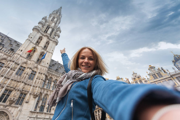 A woman takes a telephone picture on the background of the city hall in the main square Grand place in Brussels, Belgium - Foto, Imagem