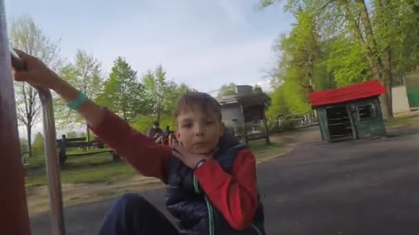 Junge reitet Attraktion im Park, zeigt, dass er krank ist, krank - Filmmaterial, Video