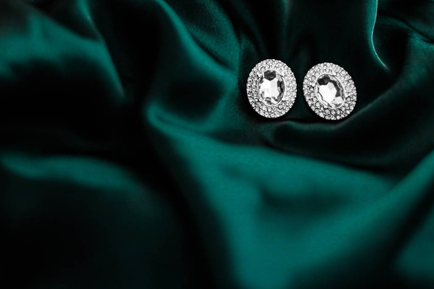 Luxury diamond earrings on dark emerald green silk, holiday glam - Photo, Image