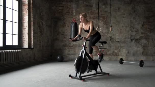La mujer en ropa deportiva está haciendo ejercicio en la bicicleta estática en el gimnasio verde. mujer de cerca en ropa deportiva está trabajando en el
 - Imágenes, Vídeo
