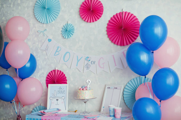 Genderparty, blauer und pinkfarbener Wandhintergrund, Jungen- oder Mädchenobjekt in der Wand und Nahaufnahme-Party-Tisch mit Kuchen und blauem und rosa Teller, Gabel und Servietten - Foto, Bild