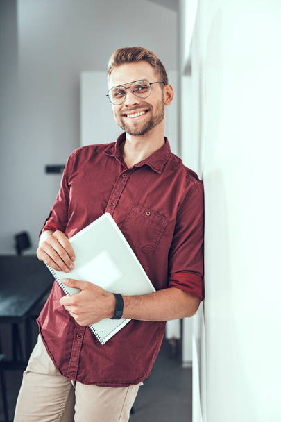 Happy male worker is standing with notebook - Photo, Image
